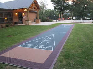 A shuffleboard court with a wooden building in the background.