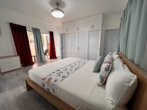 A bedroom with a bed, white wardrobe, and a ceiling fan.