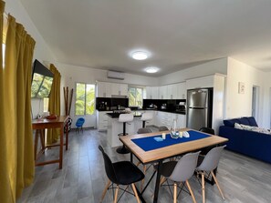 A modern kitchen with white cabinets, a black countertop, and a stainless steel refrigerator.