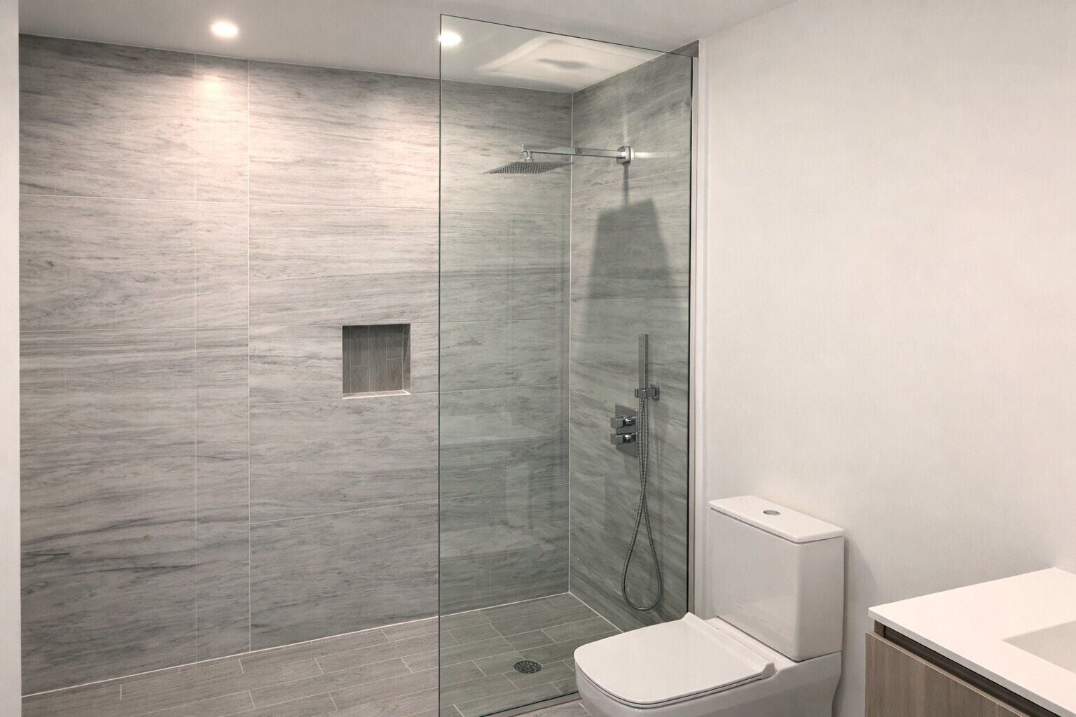 Un bagno moderno con doccia vetrata, un water e un lavandino.