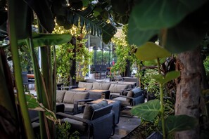 An indoor garden with seating areas, plants, and hanging lights. - Cayman Luxury Rentals at The Grove (Seven Mile Beach)