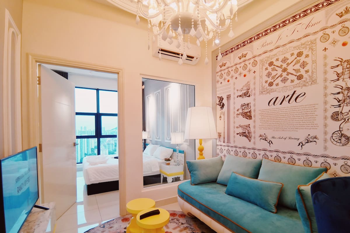 Una habitación de hotel moderna con un ventanal grande, un sofá, un espejo y un panel decorativo con la palabra 'arte'.
