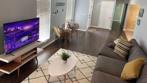 A living room with a flat-screen TV, a ceiling fan, a sofa, and a dining area with chairs and a table. - Coco's Beach House Residential Home w/ POOL (Bradenton)