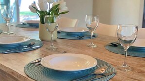 A dining table set with plates, cutlery, and wine glasses, with a vase of white flowers in the center. - Coco's Beach House Residential Home w/ POOL (Bradenton)