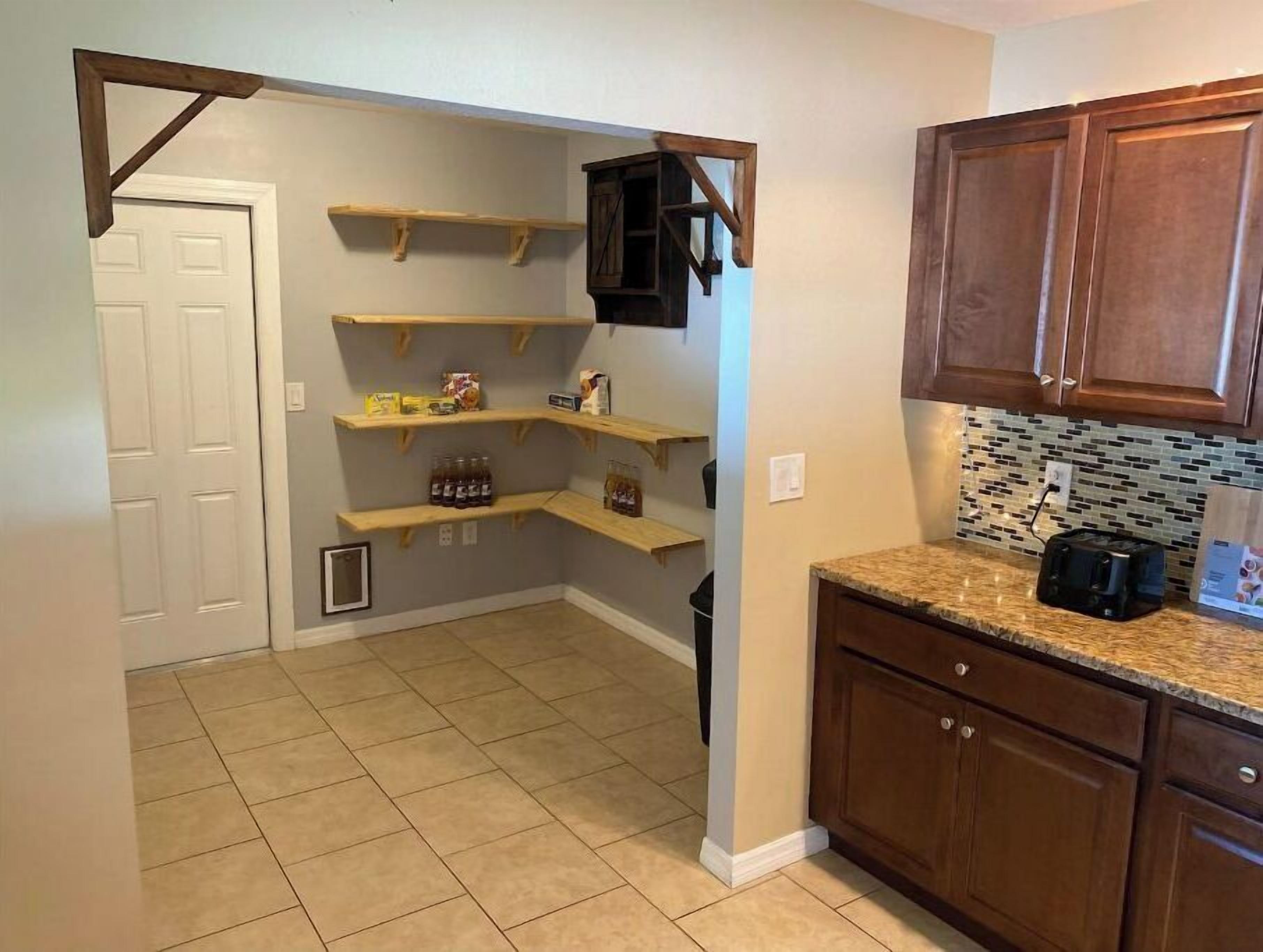 A kitchen with wooden shelves, a tiled floor, and wooden cabinets.