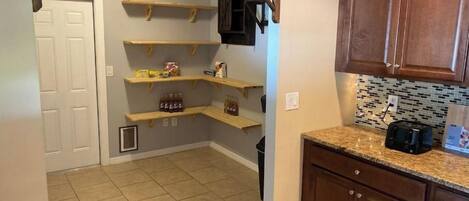 A kitchen with wooden shelves, a tiled floor, and wooden cabinets.