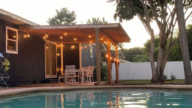 A pool area with a covered patio, outdoor furniture, and string lights. - Coco's Beach House Residential Home w/ POOL (Bradenton)
