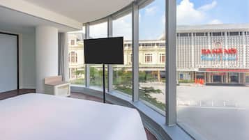 Habitación de hotel con una cama grande, un televisor de pantalla plana y vistas a un edificio con un letrero que dice "CAHANG".