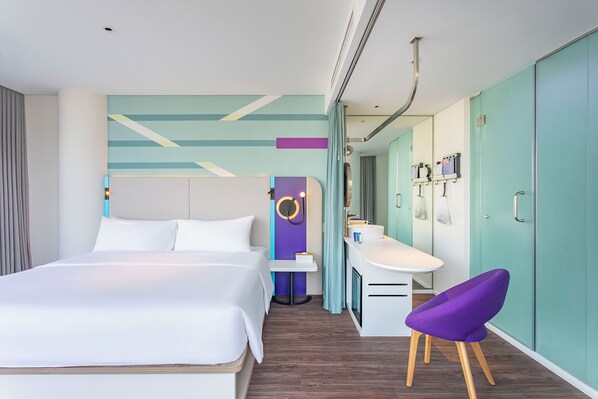 A modern hotel room with a large bed, a desk with a sink, and a purple chair. - Tru by Hilton Hanoi Station (Hanoi)