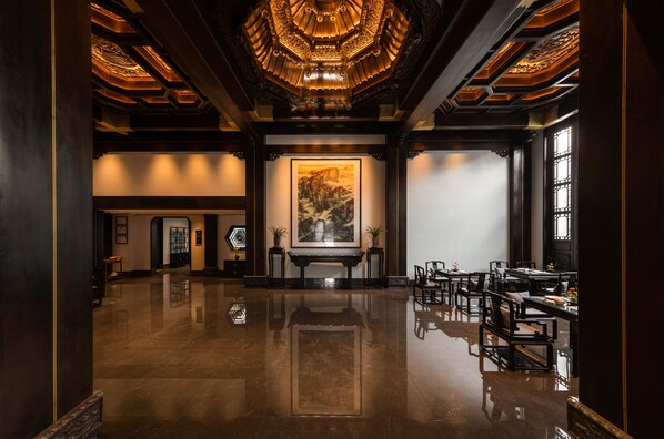 A spacious lobby with a polished floor, a large painting on the wall, and traditional wooden furniture. - San Po Hotel (Fuzhou)
