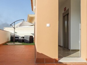 Un balcón con mobiliario exterior y una puerta que da a un espacio interior.