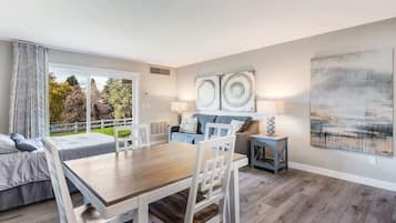 Ein modernes Wohnzimmer mit Esstisch, Stühlen, einer Couch und Blick ins Freie.