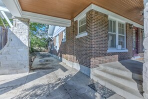 A residential house with a brick exterior, a covered porch, and a stone wall. - 2 Bedroom Bungalow - Walk To Overton Park, Memphis Zoo & More! (Memphis)