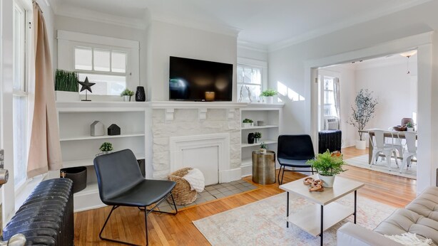 A modern living room with a fireplace, a flat-screen TV, and a dining area with a table and chairs. - 2 Bedroom Bungalow - Walk To Overton Park, Memphis Zoo & More! (Memphis)