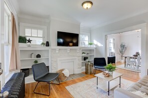 Una sala moderna con chimenea, televisor de pantalla plana y comedor con mesa y sillas.