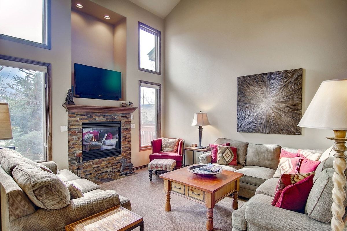 A living room with a fireplace, a television mounted above it, and a large abstract painting on the wall.