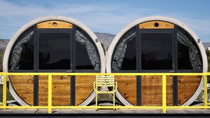 Two large, semi-circular structures with black doors and mesh windows, enclosed by a yellow fence. - ChangoMango (La Ventana)