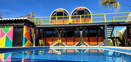 Una piscina al aire libre, sombrillas, sillones reclinables de piscina