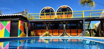 Una piscina al aire libre, sombrillas, sillones reclinables de piscina