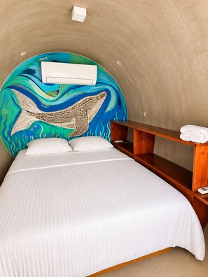 Una habitación con una cama, un banco de madera y un mural en la pared.