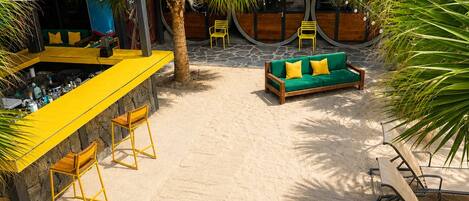 Un bar junto a la playa con áreas de estar y una piscina.