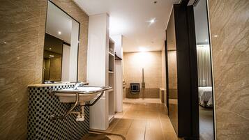 A modern bathroom with a sink, mirror, and shower area.