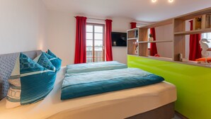 A compact room with a bed, a sofa, a TV, and a small wooden shelf. - Vacation apartment "Jakobo" 44sqm, balcony (Eggstätt)
