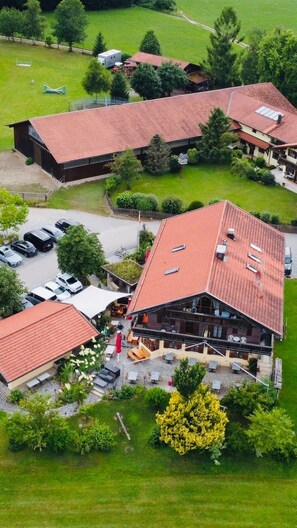 A multi-story building with a red-tiled roof, a parking area, and a well-maintained lawn. - "Jakobo" Vacation Apartment, 44 m², balcony (Eggstätt)