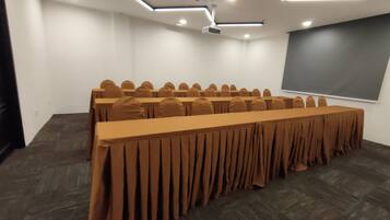 A conference room with a long table, rows of chairs, a projector, and a screen.
