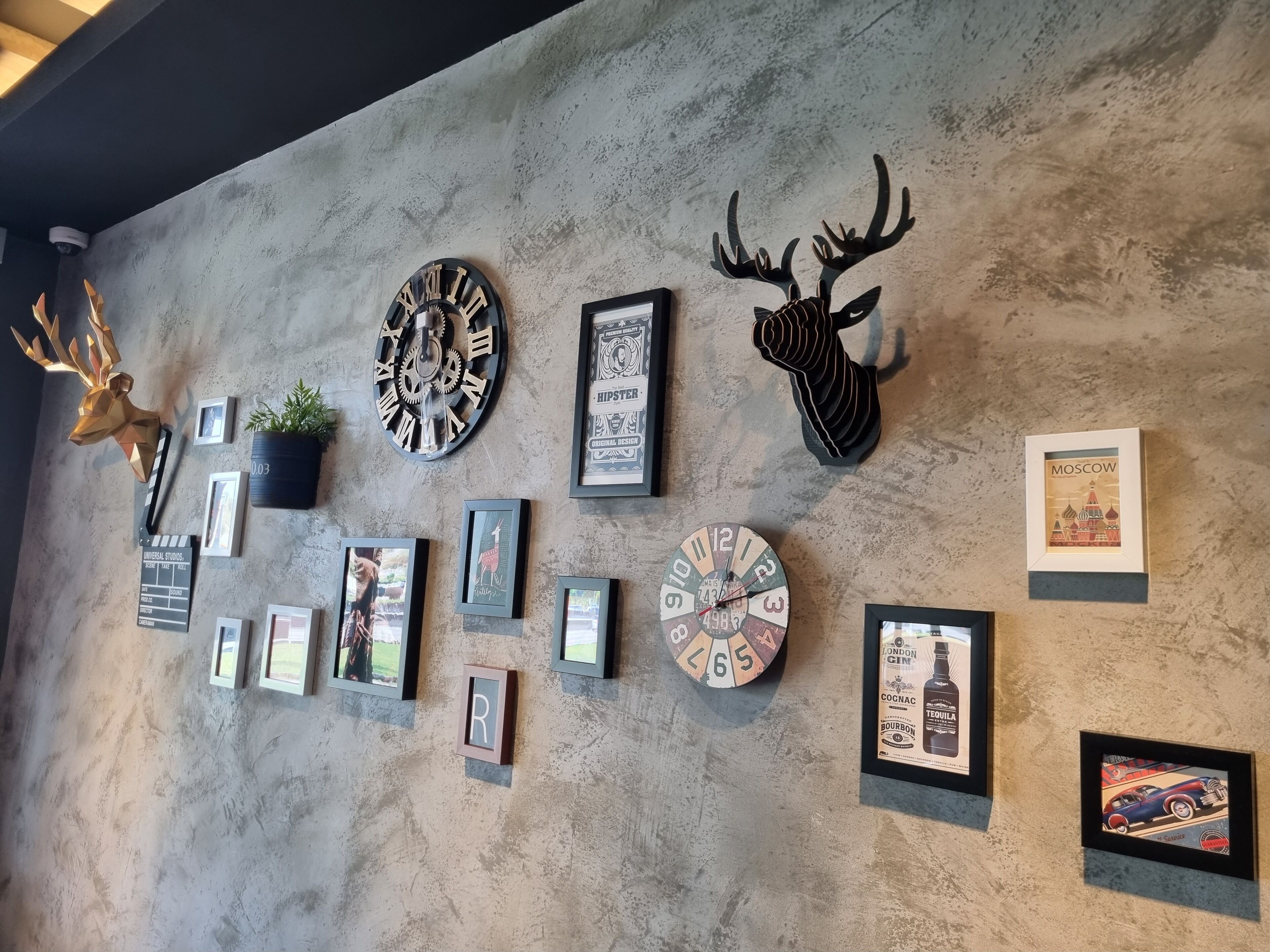 A wall with various decorative items including clocks, a deer head, framed pictures, and a Moscow poster.