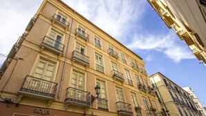 A multi-story building with balconies, a storefront labeled 'ROLER,' and a sign for 'LA ALACENA DE FRANCIS.'