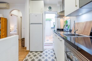A modern kitchen with a refrigerator, sink, and wooden cabinets.