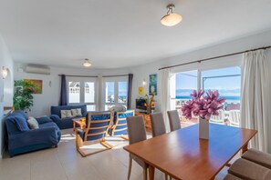 Un salon moderne comprenant un canapé, une table à manger et des chaises, un téléviseur et un balcon avec vue.