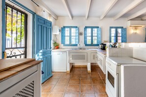 A kitchen with blue cabinets, white appliances, and a tiled floor.