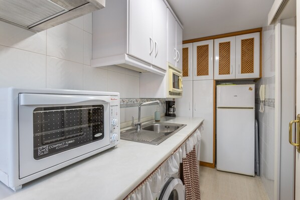Una cocina compacta equipada con microondas, fregadero y refrigerador.