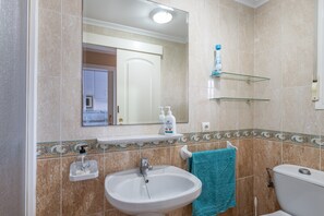 Een badkamer met een wastafel, spiegel en toilet.