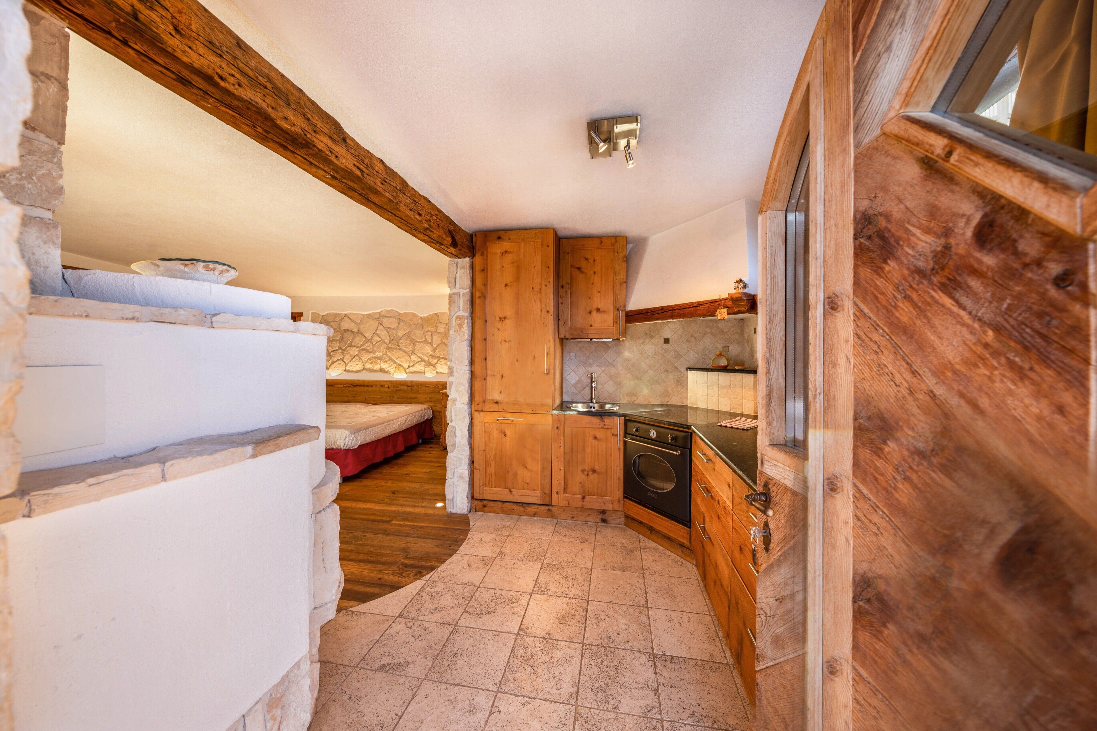 Una cocina compacta con armarios de madera, una pared de piedra y un horno empotrado.