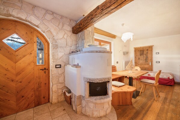 Une cheminée en pierre avec un banc, une porte en bois et une table à manger avec des chaises.