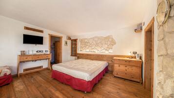 Ein Schlafzimmer mit Bett, Holzk dresser, Fernseher, Steinwand und einer Uhr.