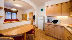 Une cuisine compacte dotée de meubles en bois, d’un four à micro-ondes, d’un réfrigérateur et d’un coin repas avec une table et des chaises en bois.