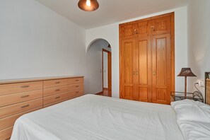Een slaapkamer met een bed, een houten garderobe en een dressoir.