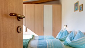 Puerta de madera con cerradura y pomo, que da a un cuarto con almohadones a rayas y una cama.