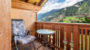 Un balcón de madera con vista a un paisaje montañoso.