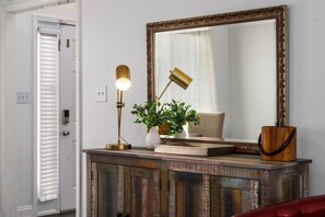 Una habitación con un armario de madera, un espejo, una lámpara y una planta en maceta.