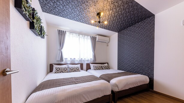 A bedroom with two beds, a window with curtains, a ceiling light, and a wall-mounted air conditioner. - ID STAY Kawaguchiko 5 (Fujikawaguchiko)