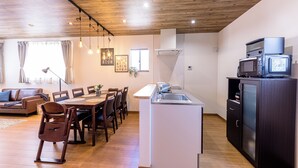 A modern kitchen with a central island, wooden ceiling, and a dining area with a brown leather couch and wooden chairs. - ID STAY Kawaguchiko 5 (Fujikawaguchiko)