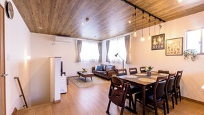 A spacious living area with a wooden ceiling, a dining table with chairs, a sofa, and a coffee table. - ID STAY Kawaguchiko 5 (Fujikawaguchiko)