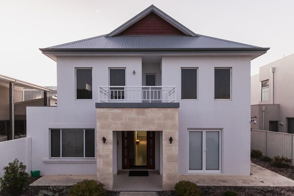 A modern two-story house with a balcony, large windows, and a stone entrance. - southbeach-house - Stylish & Spacious beach mansion (South Fremantle)