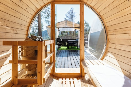 A wooden cabin with a circular window, a deck, and a grill area visible through the window.. TOCORO. Mt.Fuji CAMP&GLAMPING