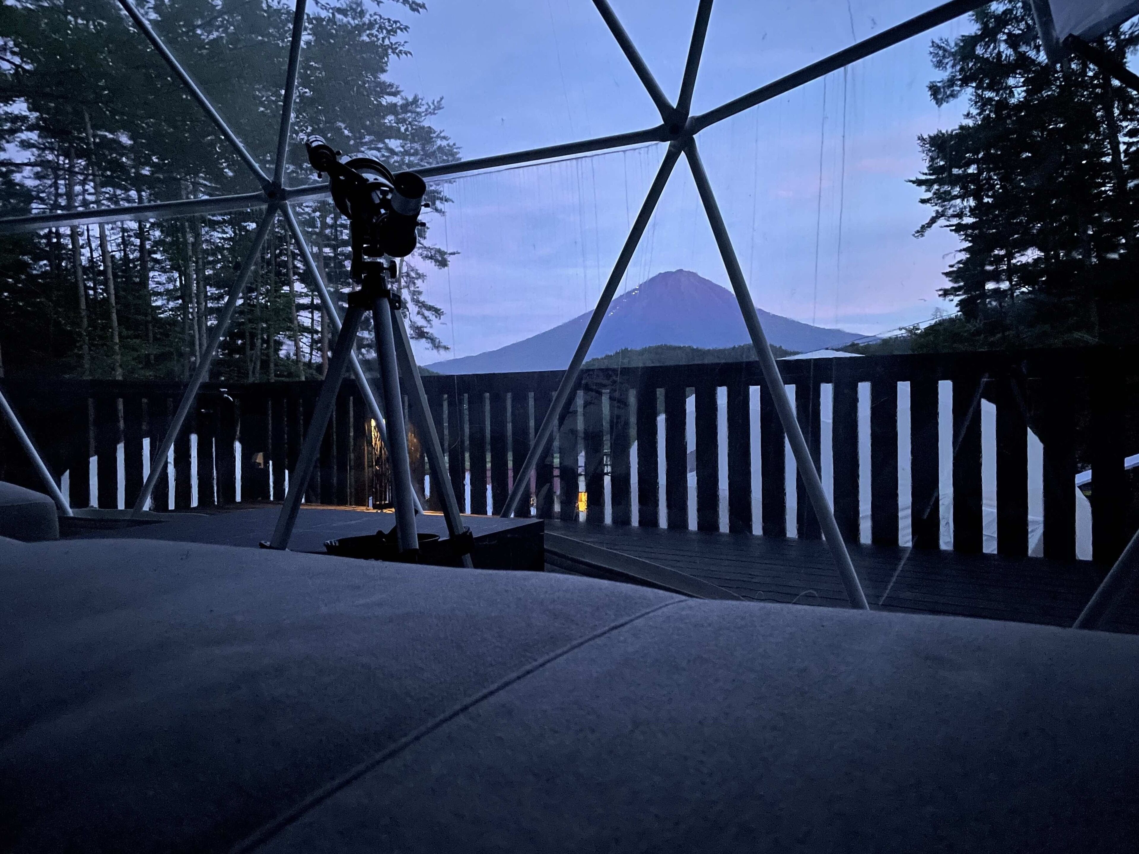 A modern architectural structure with a metal framework and a wooden fence.